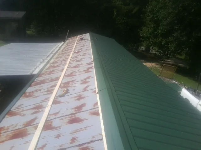 Old rusted panels beside newly installed green metal roofing — Wind Damage Roof Repair by Roofing Brothers in Jeffersonton