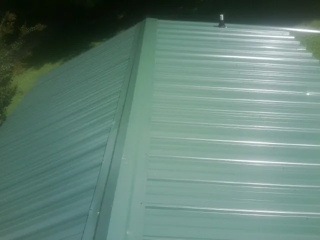 New green metal panels meeting at the ridge of a roof — Flat Roof Repair work by our crew in Jeffersonton