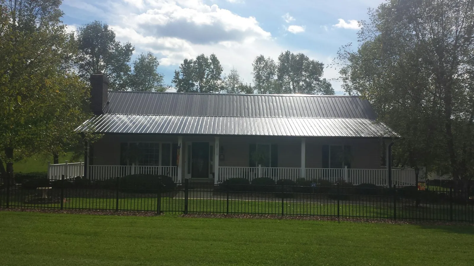 Gray metal roof on a brick ranch with a full width front porch — Gutter Guard Installation work by our crew in Jeffersonton
