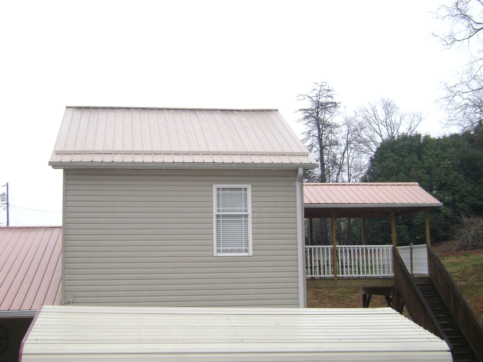 Tan metal roofs on a two story addition and attached porch, from a Roof Replacement job in Jeffersonton