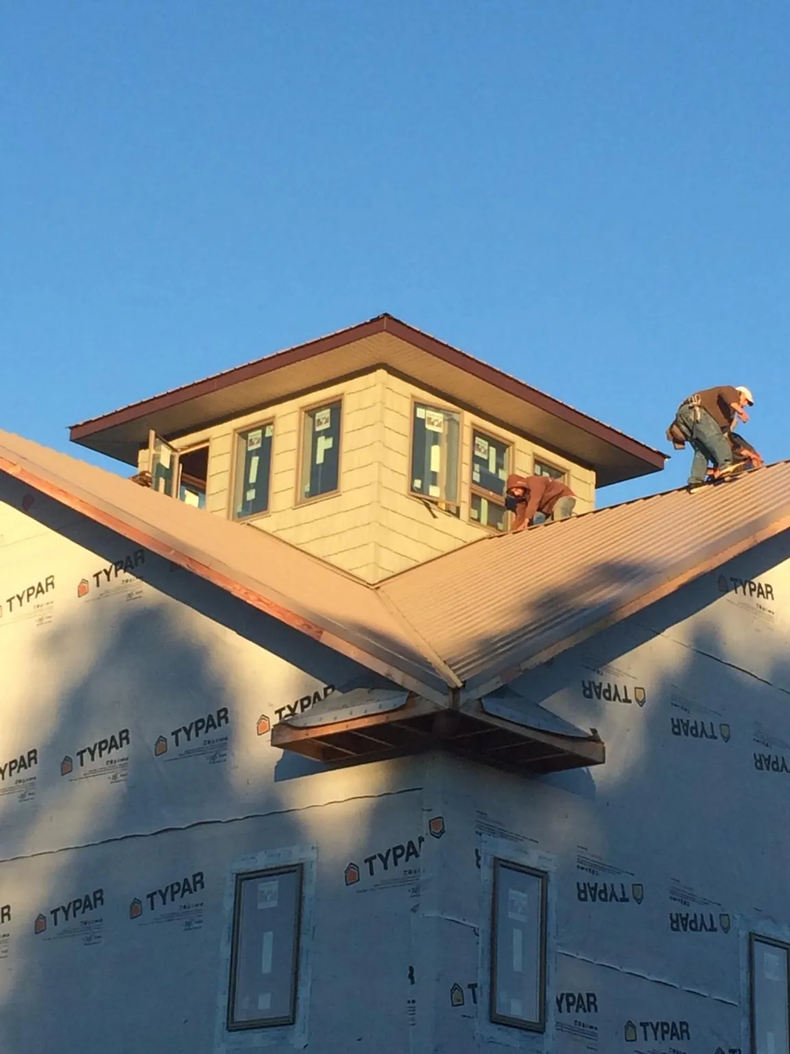 Roofers working around a rooftop cupola on a new metal roof at sunset — Roof Waterproofing in Jeffersonton by Roofing Brothers